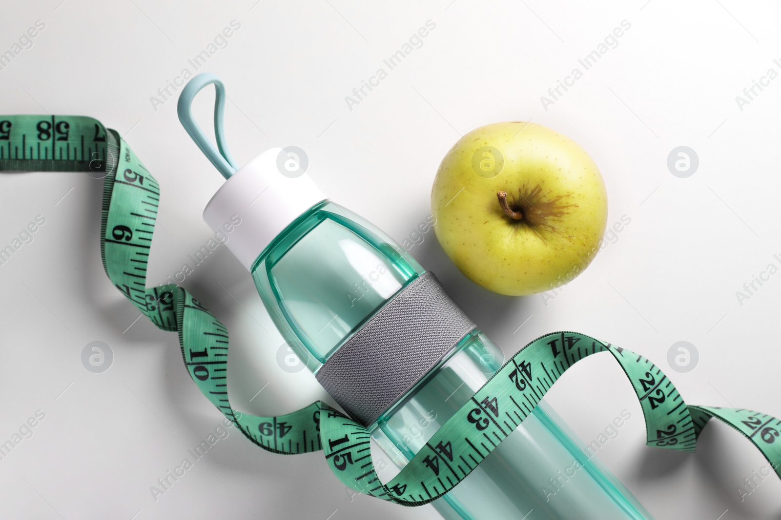 Photo of Measuring tape, apple and bottle with water on white background, flat lay. Weight control concept