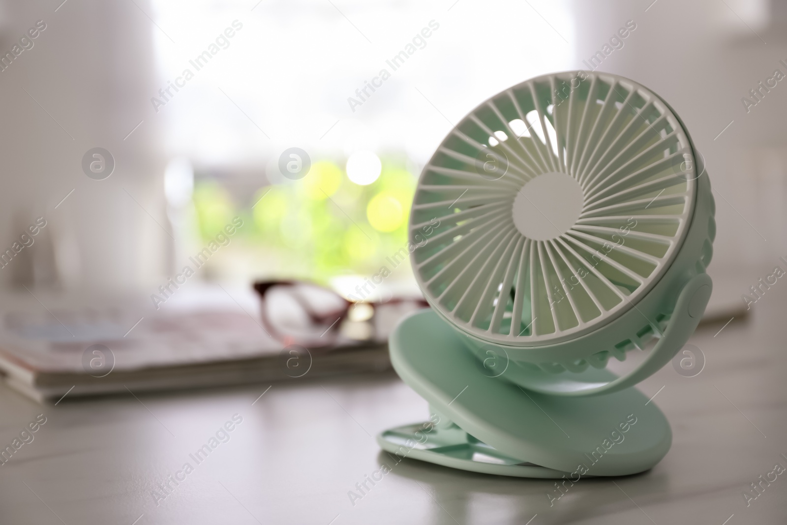 Photo of Modern portable fan on white marble table indoors, space for text. Summer heat