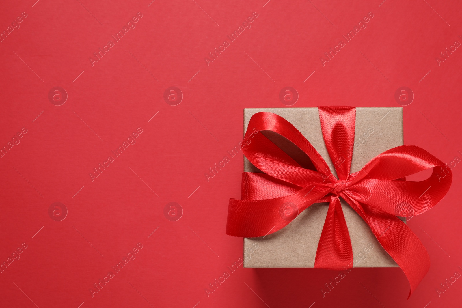 Photo of Beautiful gift box with bow on red background, top view. Space for text