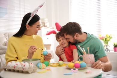 Photo of Happy family painting Easter eggs at table indoors