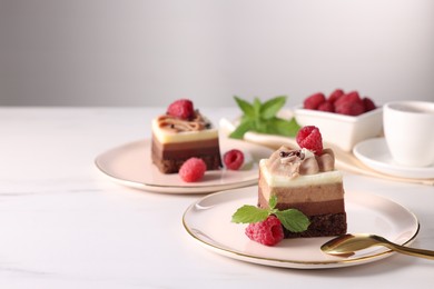 Photo of Pieces of triple chocolate mousse cake with raspberries served on white marble table, closeup. Space for text