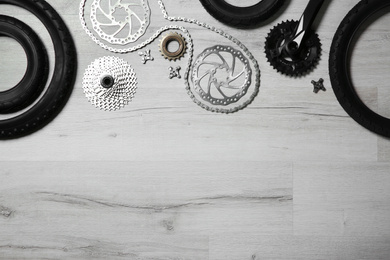 Set of different bicycle parts on wooden background, flat lay. Space for text
