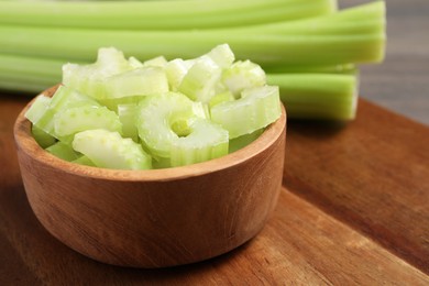 Photo of Bowl with fresh green cut celery on wooden board, closeup. Space for text
