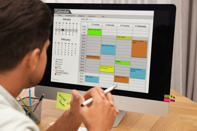 Photo of Man using calendar app on computer in office, closeup