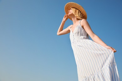 Beautiful woman with straw hat against blue sky on sunny day, space for text