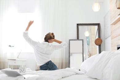 Young happy woman stretching on bed at home. Lazy morning