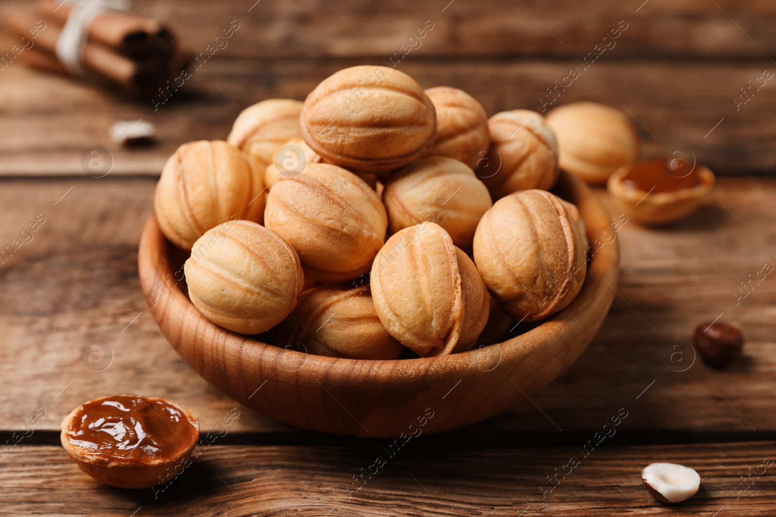 Photo of Homemade walnut shaped cookies with boiled condensed milk on wooden table, closeup