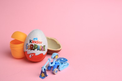 Photo of Sveti Vlas, Bulgaria - July 3, 2023: Kinder Surprise Eggs, open plastic capsule and toy on pink background, space for text