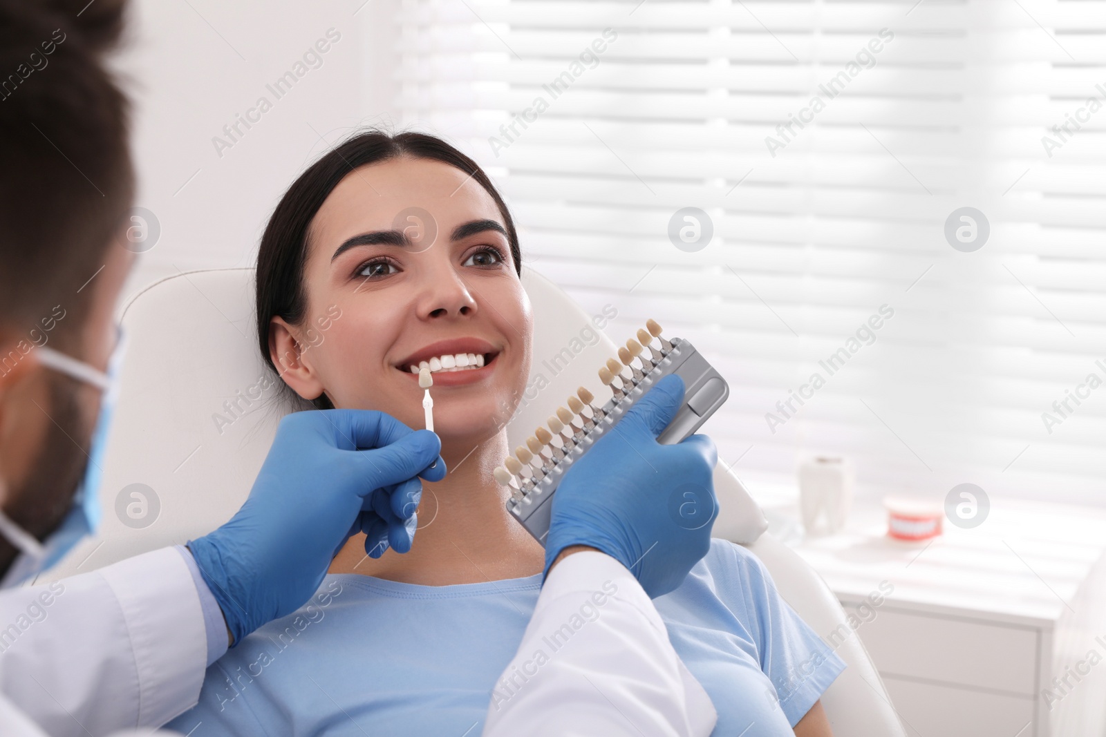 Photo of Dentist checking young woman's teeth color in clinic