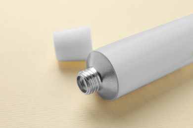 Photo of Open tube of ointment on beige background, closeup. Space for text