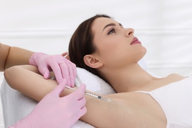 Photo of Cosmetologist injecting young woman's armpit in clinic. Treatment of hyperhidrosis