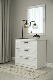 Photo of Hallway with stylish chest of drawers and mirror. Interior design