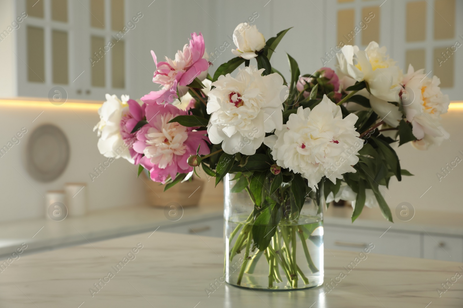 Photo of Bouquet of beautiful peonies on table in kitchen