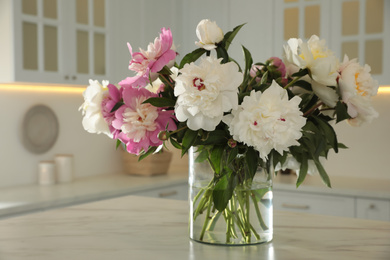 Bouquet of beautiful peonies on table in kitchen