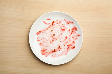 Photo of Dirty plate with food leftovers on wooden background, top view