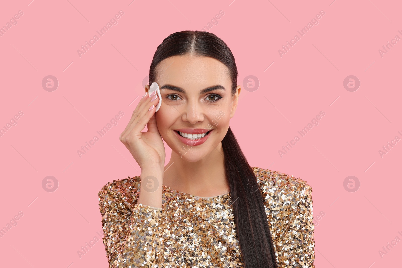 Photo of Beautiful woman removing makeup with cotton pad on pink background