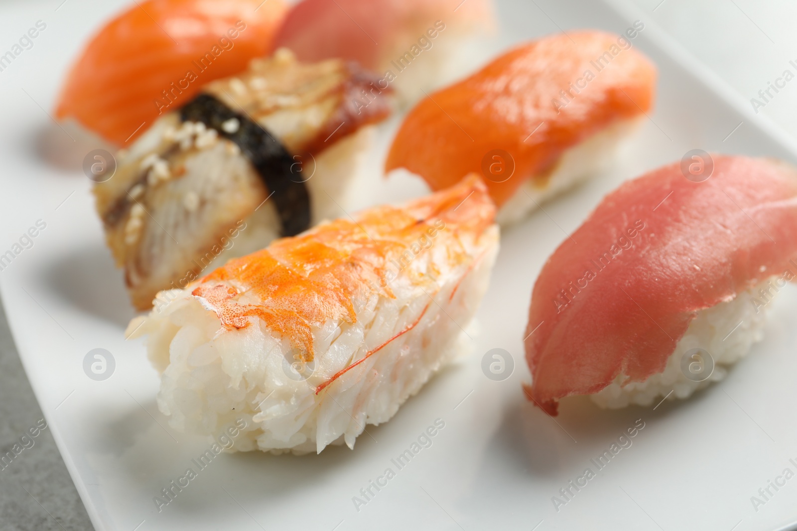 Photo of Plate with delicious nigiri sushi on grey table, closeup