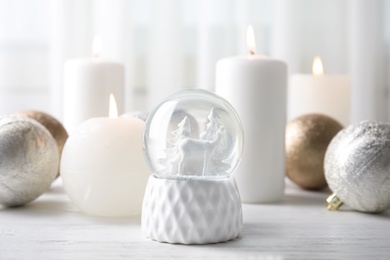 Photo of Snow globe with Christmas balls and candles on table