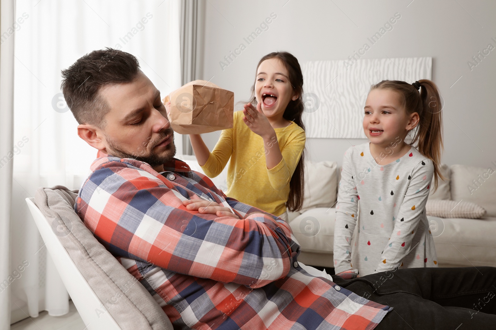 Photo of Cute little children popping paper near father while he sleeping at home