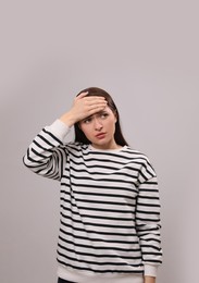 Woman suffering from headache on light grey background. Cold symptoms