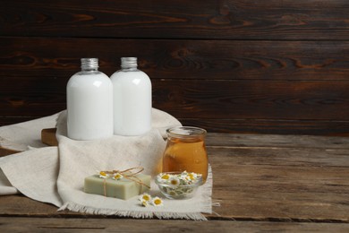 Photo of Composition with chamomile flowers and cosmetic products on wooden table, space for text