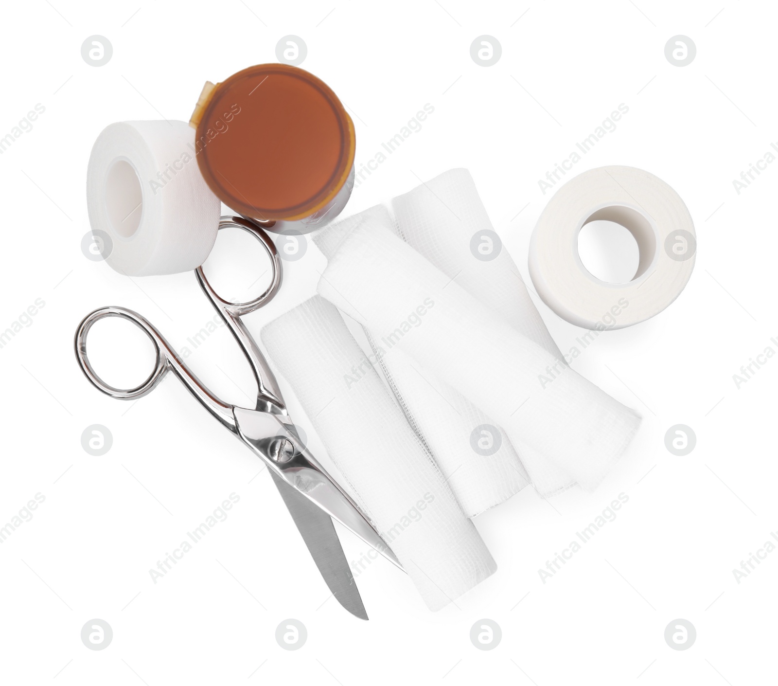 Photo of Medical bandage rolls, pills, sticking plaster and scissors on white background, top view