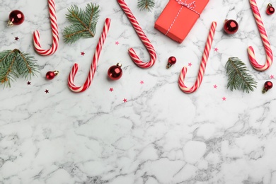 Photo of Flat lay composition with candy canes and Christmas decor on white marble table