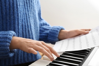 Photo of Young woman playing piano at home, closeup