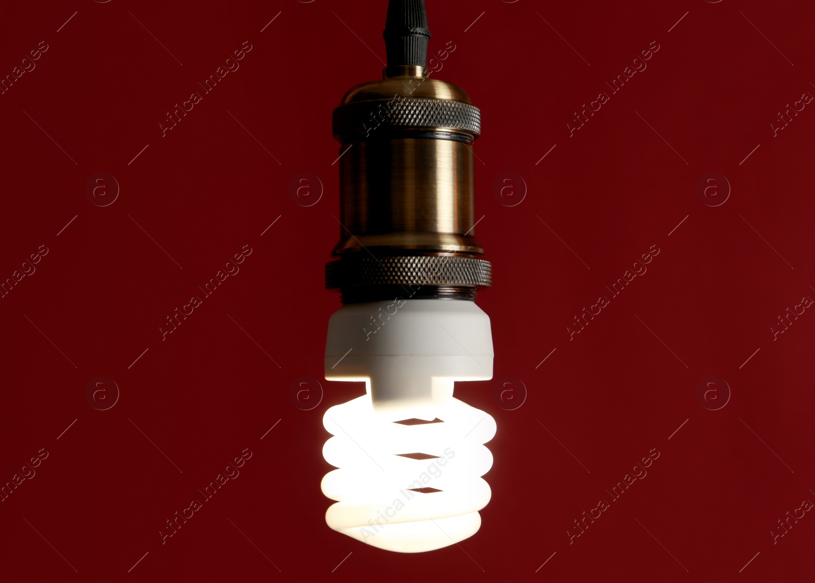 Photo of Hanging fluorescent lamp bulb against dark red background