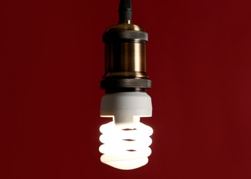 Hanging fluorescent lamp bulb against dark red background