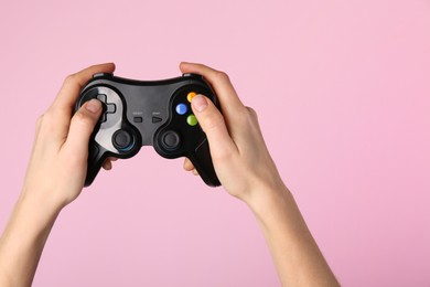 Photo of Woman using game controller on pink background, closeup