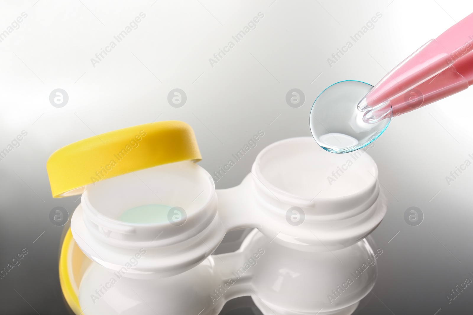 Photo of Taking contact lens from case on grey background, closeup