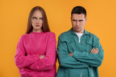 Photo of Portrait of resentful couple with crossed arms on orange background