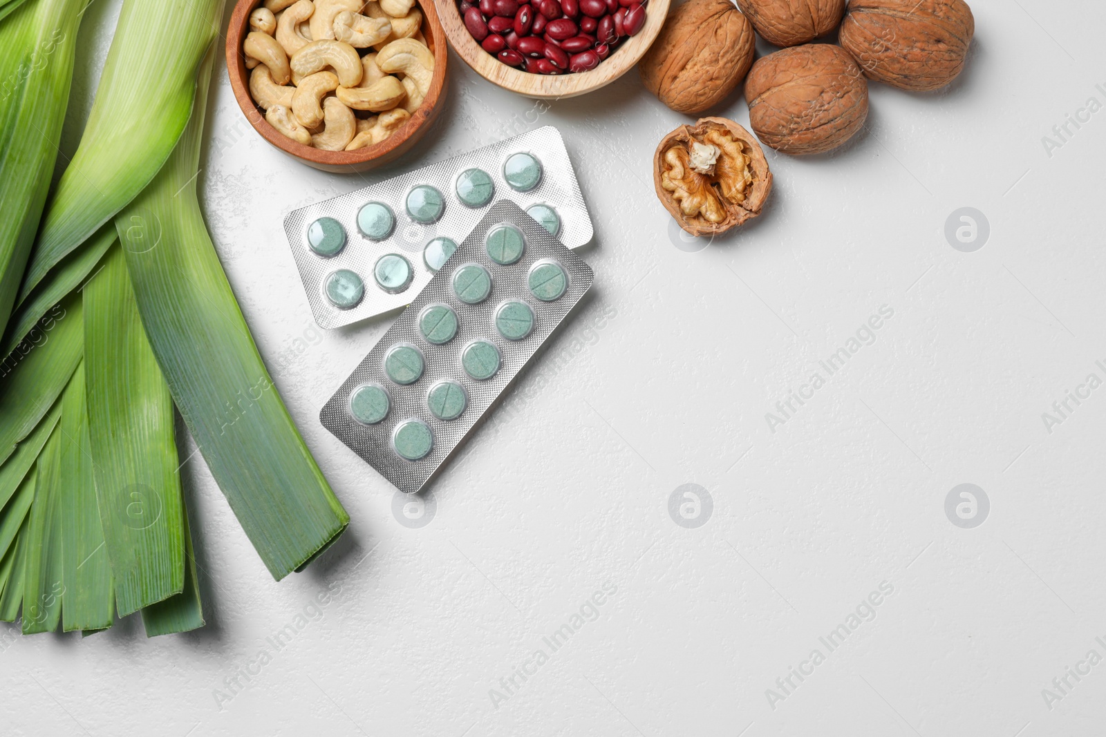 Photo of Blisters of pills and foodstuff on white table, flat lay with space for text. Prebiotic supplements