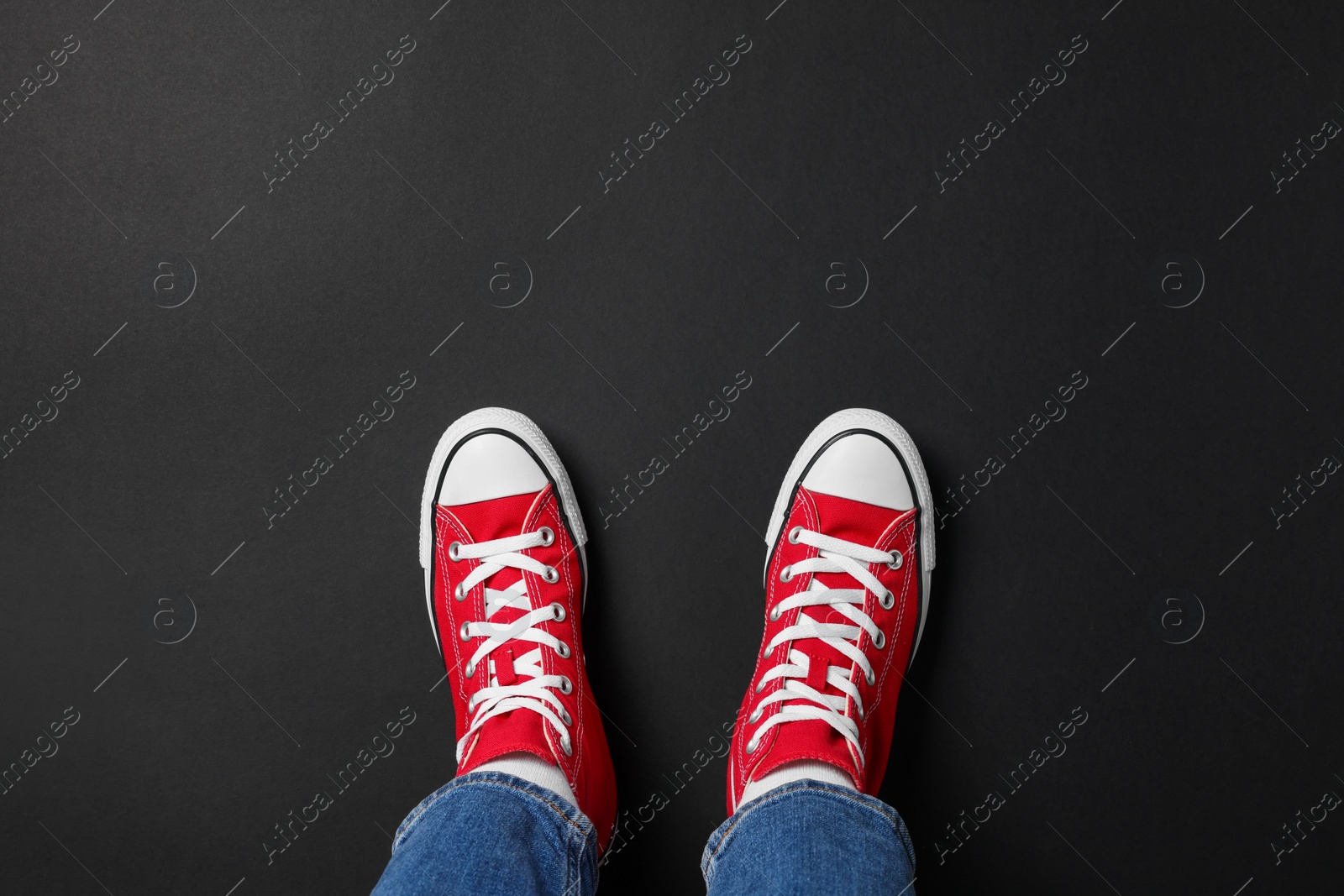 Photo of Woman in stylish gumshoes on black background, top view. Space for text