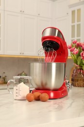 Photo of Modern red stand mixer, eggs and container with flour on white marble table in kitchen