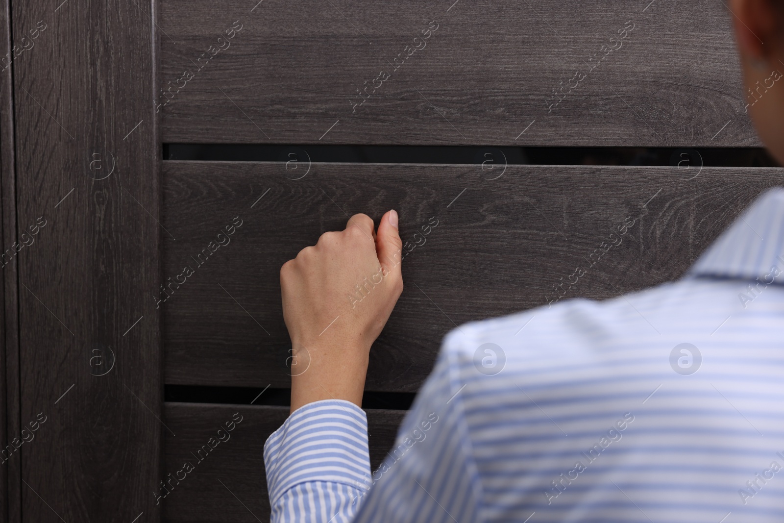 Photo of Woman knocking on door indoors, closeup view