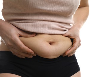 Woman touching belly fat on white background, closeup. Overweight problem