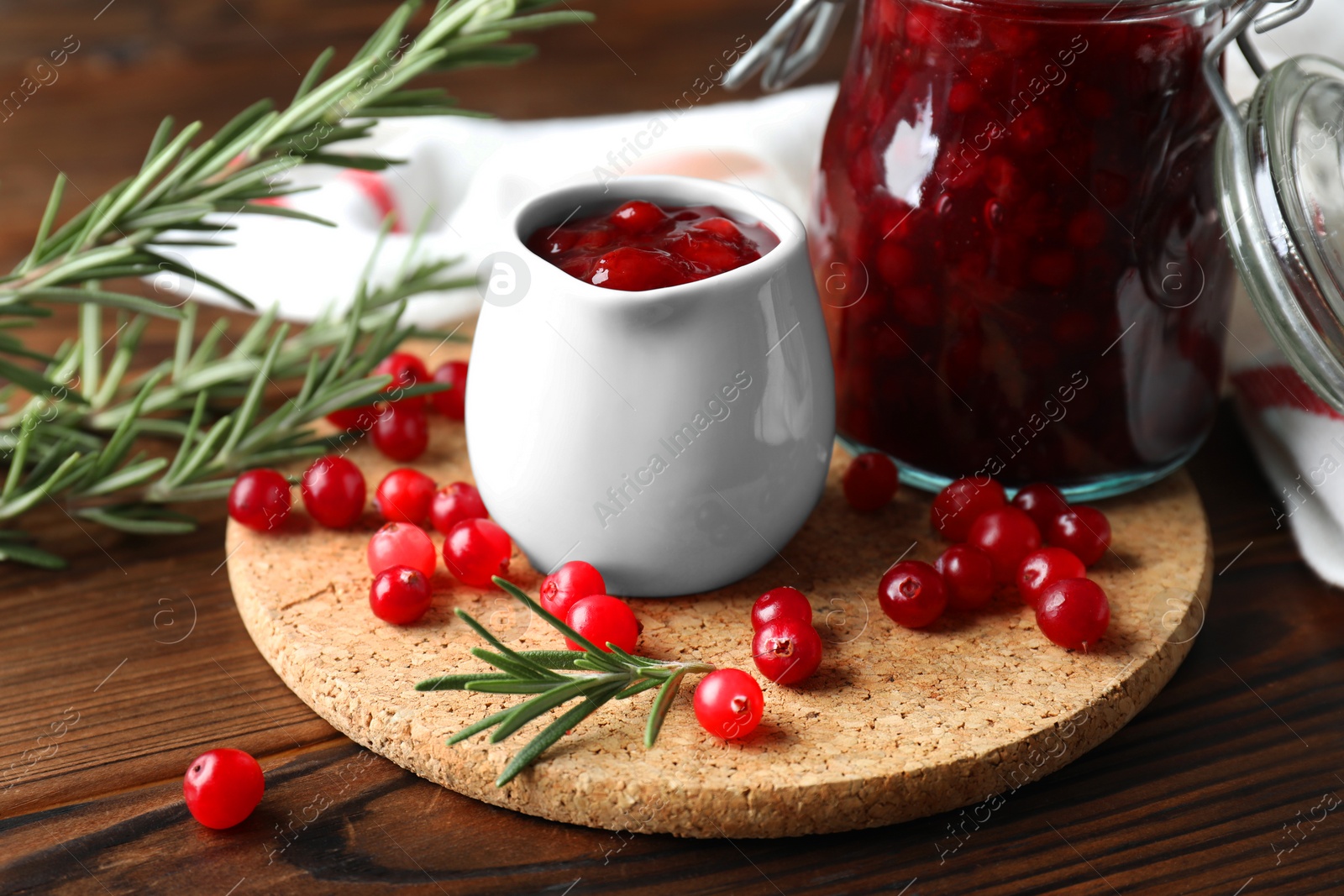 Photo of Cranberry sauce, fresh berries and rosemary on wooden table