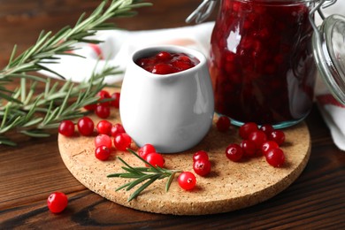 Photo of Cranberry sauce, fresh berries and rosemary on wooden table