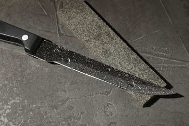 Photo of Knife and sharpening stone on grey stone background