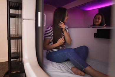 Photo of Happy young woman sitting in capsule of pod hostel