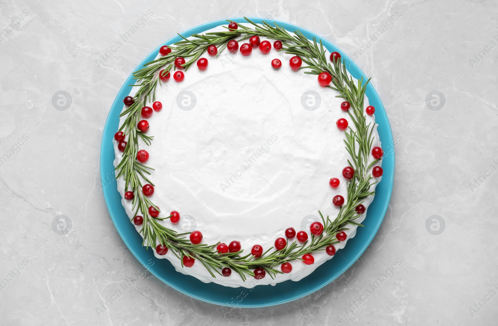 Photo of Traditional Christmas cake decorated with rosemary and cranberries on light grey marble table, top view