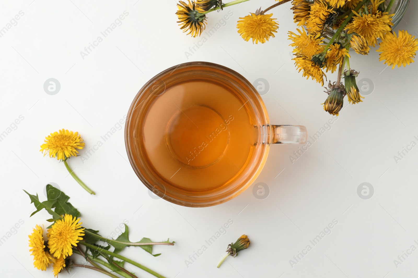 Photo of Delicious fresh tea and dandelion flowers on white table, flat lay