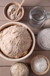 Fresh sourdough, flour and water on wooden table, flat lay