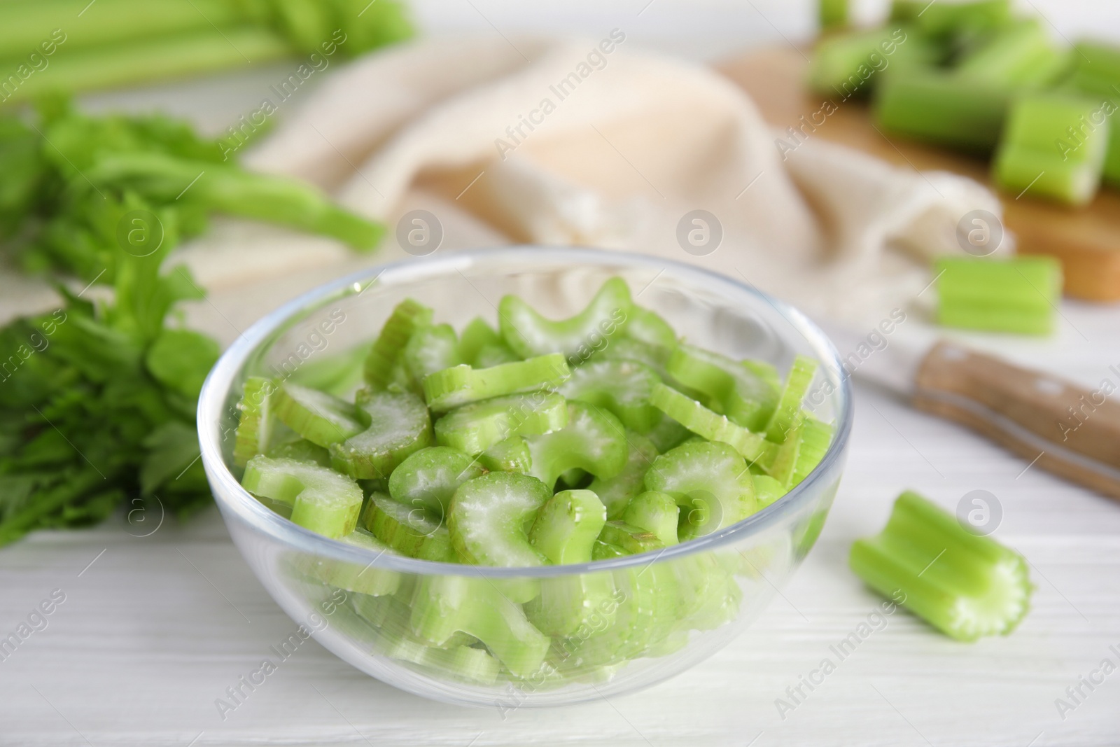 Photo of Cut celery in glass bowl on white wooden table