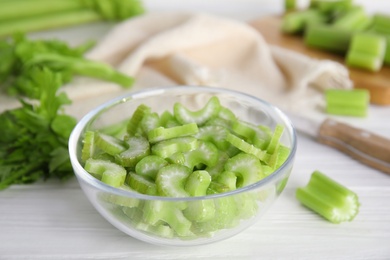 Photo of Cut celery in glass bowl on white wooden table