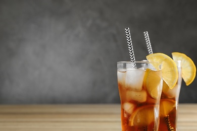 Photo of Glasses of tasty ice tea with lemon on grey background, space for text