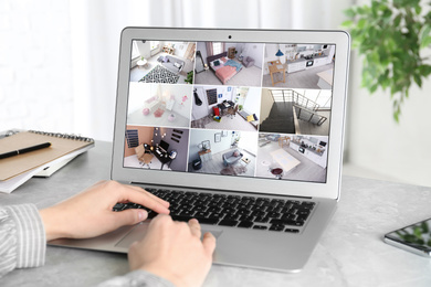 Image of Woman monitoring modern cctv cameras on laptop indoors, closeup. Home security system