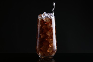 Glass of refreshing soda water with ice cubes on black background